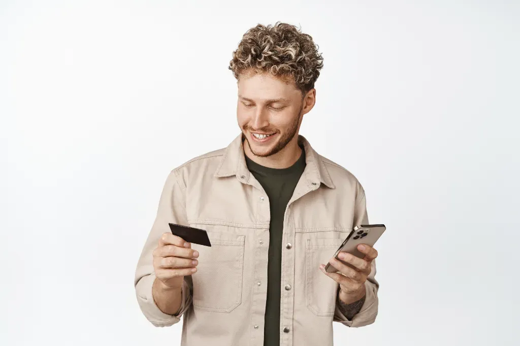 mężczyzna trzymający w kartę płatniczą i telefon